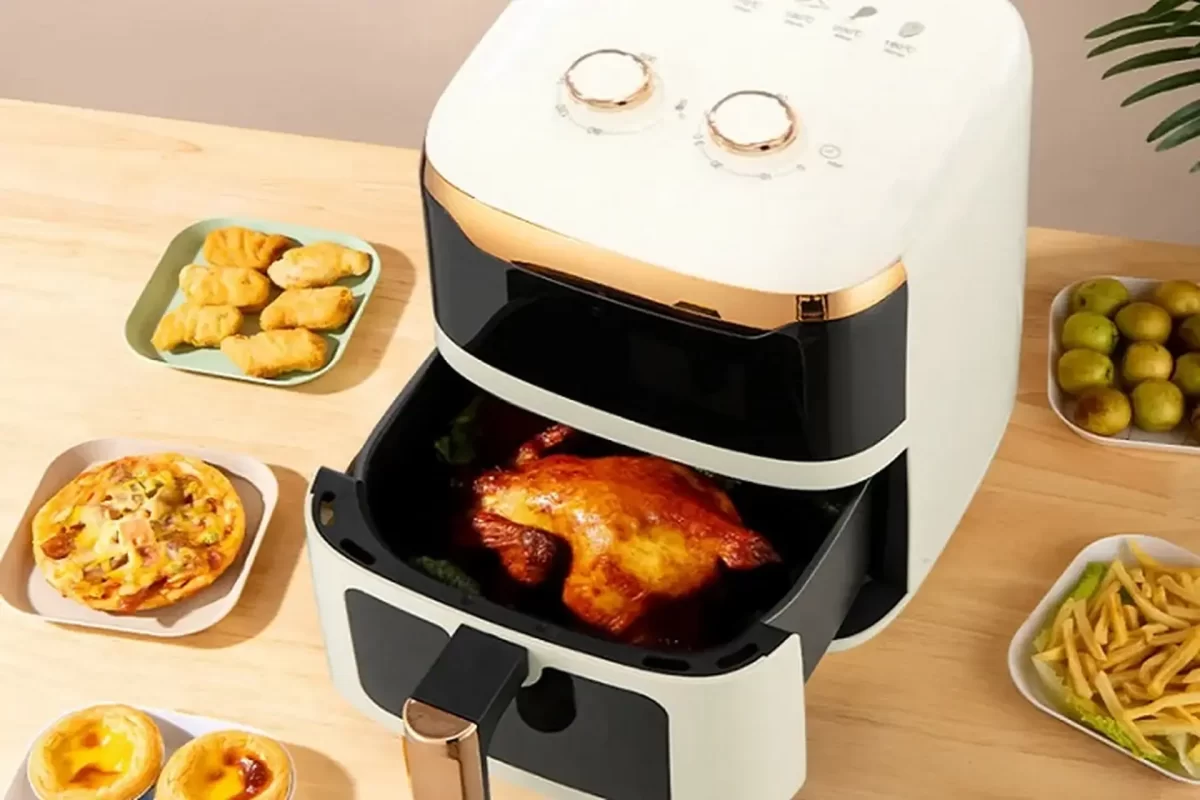 Hình ảnh nồi chiên không dầu Camel với món gà nướng vàng ươm bên trong, đặt cạnh đĩa khoai tây chiên