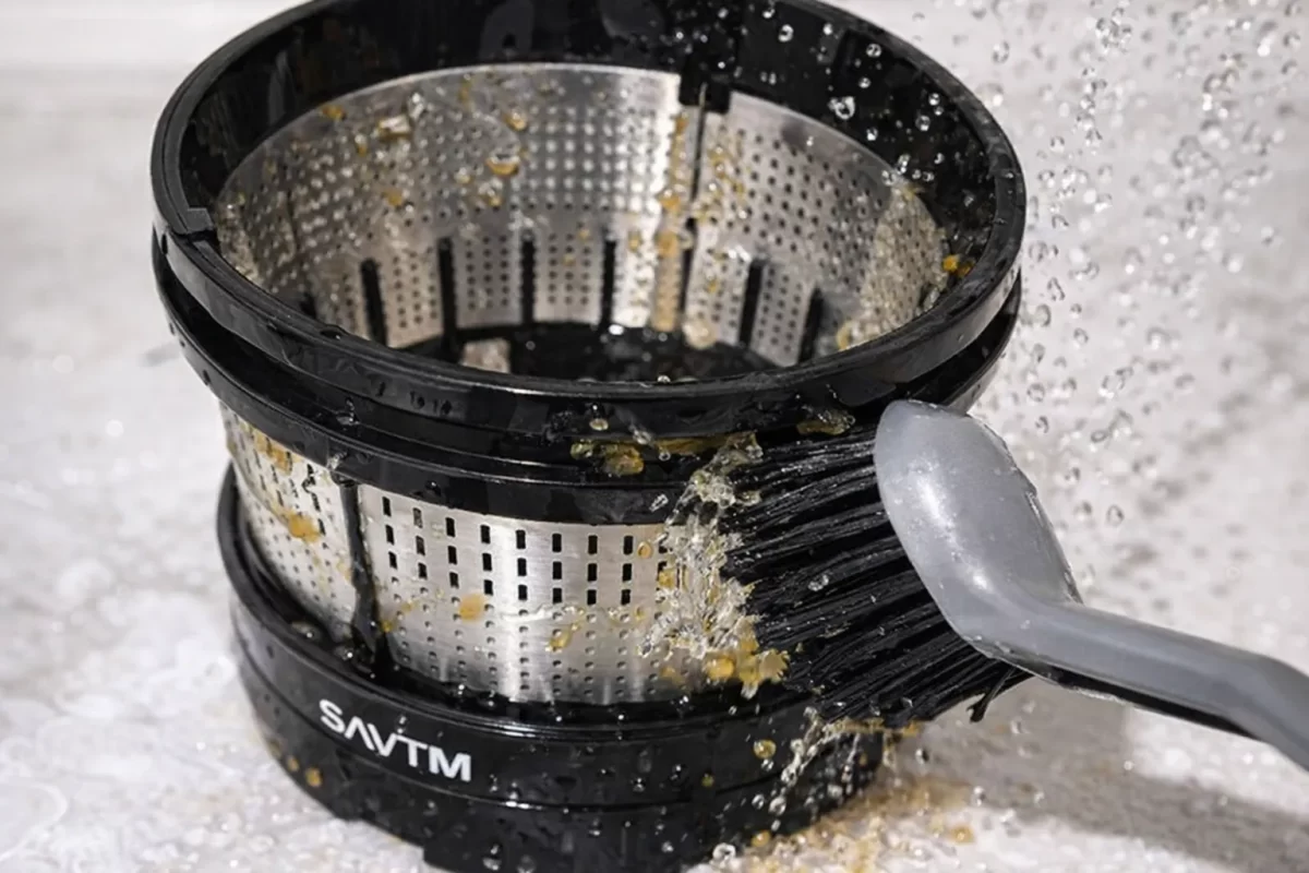 Cận cảnh lưới lọc inox của máy ép chậm Savtm và cọ vệ sinh chuyên dụng giúp làm sạch bã trái cây dễ dàng
