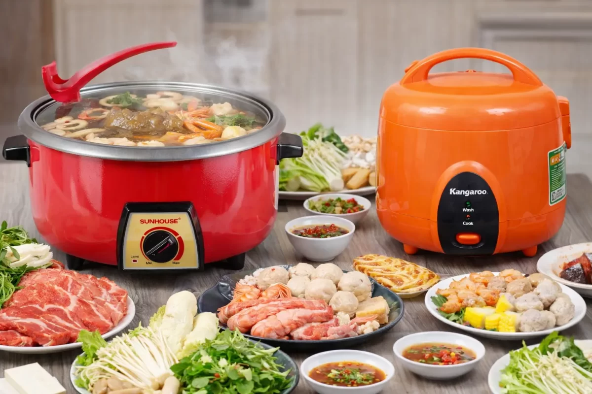 Hình ảnh so sánh nồi lẩu điện Sunhouse màu đỏ rực rỡ và nồi lẩu điện Kangaroo màu cam bắt mắt đặt trên bàn tiệc lẩu đầy ắp thức ăn]